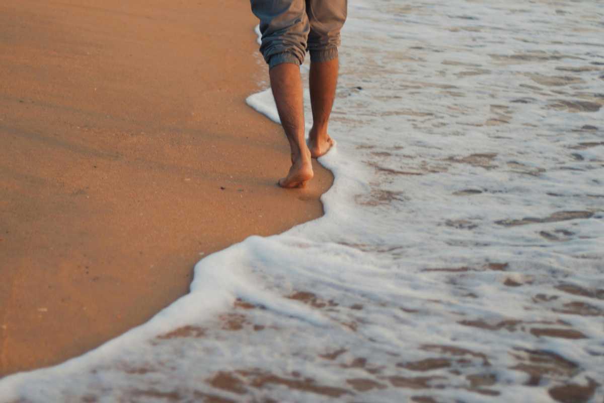 Vista panoramica della Torre Marrana immersa nella vegetazione mediterranea di Capovaticano, luce dorata al tramonto. Includere la costa e il mare sullo sfondo.